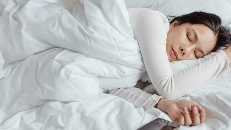 Woman sleeping in bed with white sheets